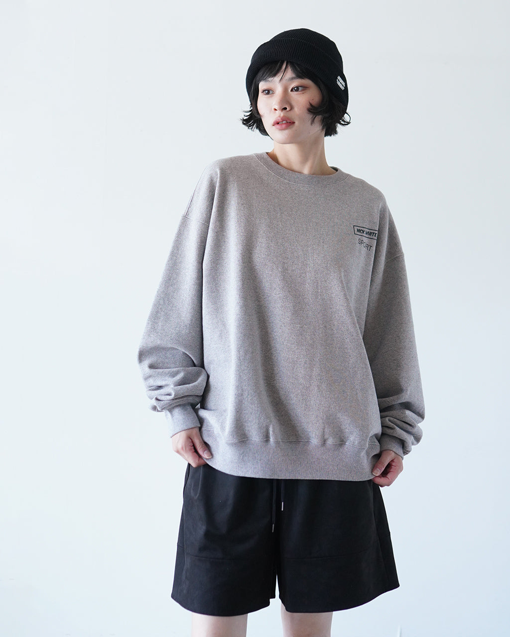 グレーのクルーネックスウェットを着用した女性の全身。ゆったりシルエットで袖口が絞らずリラックス感のあるデザインです。