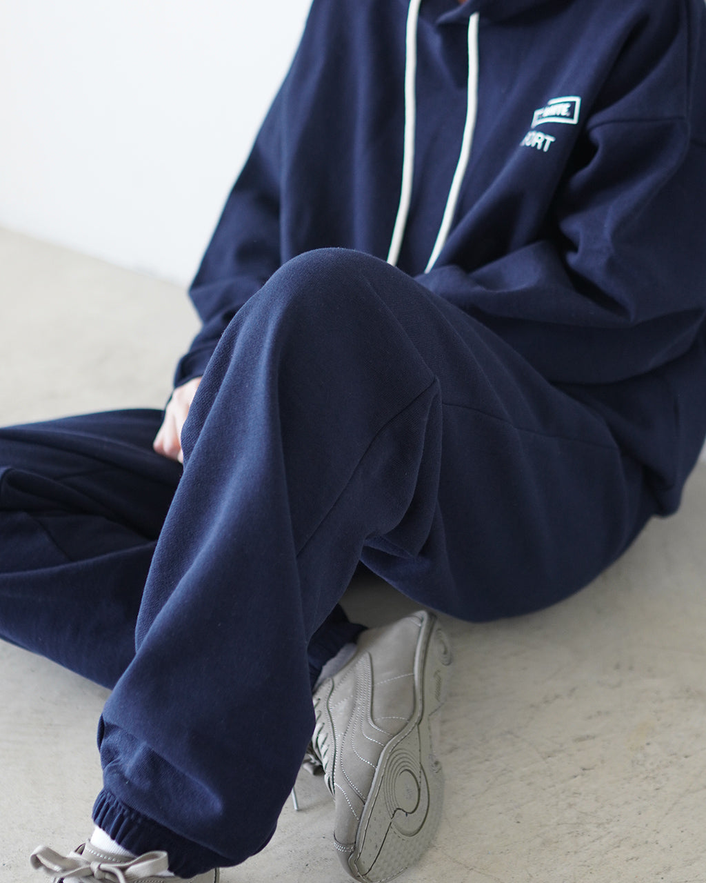 navyフーディと合わせたリラックスシルエットのスウェットパンツ。厚みのある生地と裾のリブが特徴で、腰周りと太もものゆとり感を描く着用イメージ