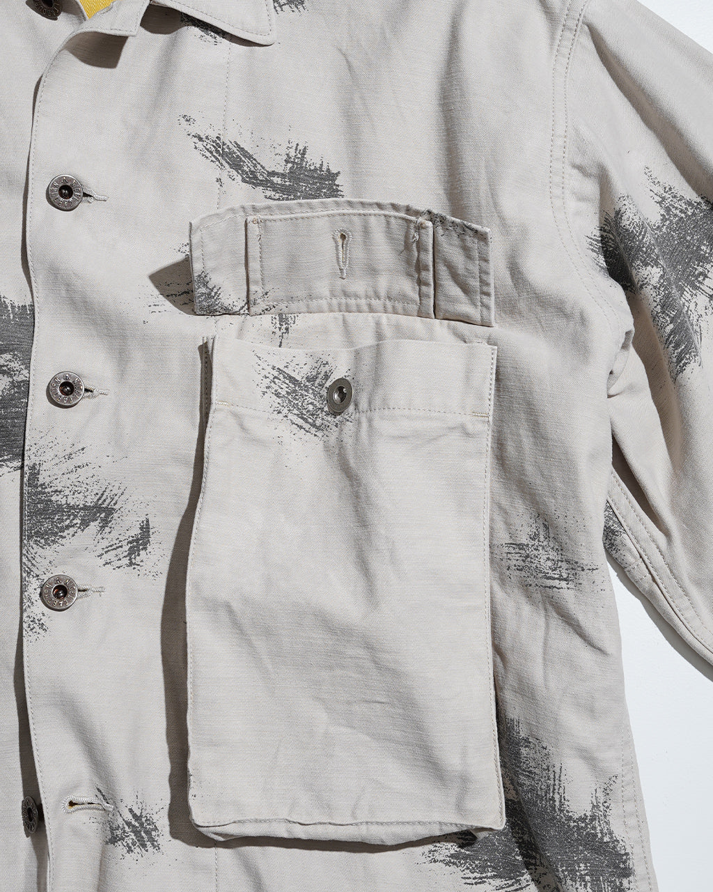 前面アップの着用感とポケットが際立つ、淡いベージュのFIELD JACKET FADE CAMOの表地。肩と胸ポケット、袖口のディテールが確認できるショット