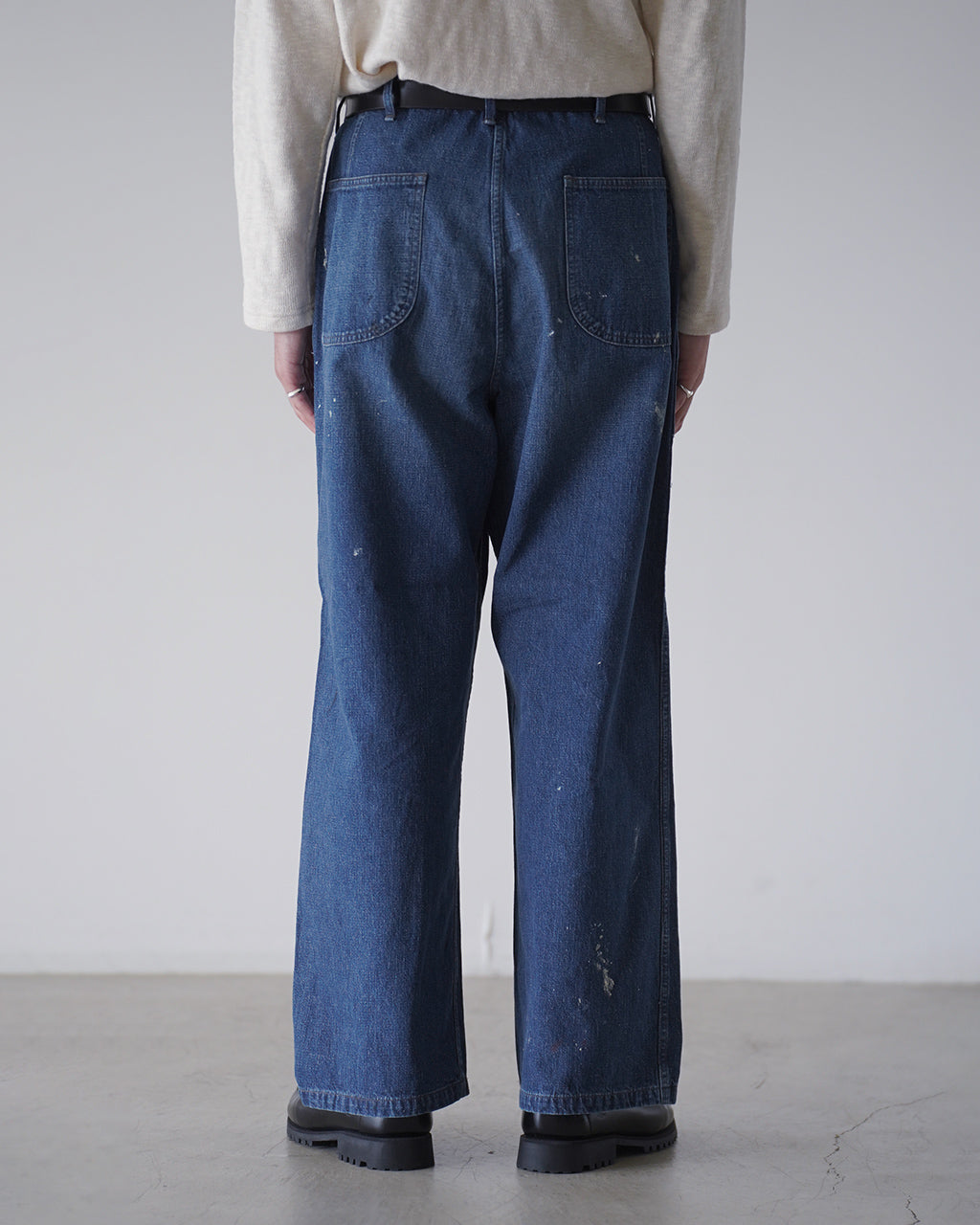 バックスタイルのデニムパンツ。やや高めのウエストとゆとりのあるワイドなヒップ周りが特徴で、左ポケット周辺に淡いインディゴの色ムラが見える。裾まで真っ直ぐのストレートシルエット。