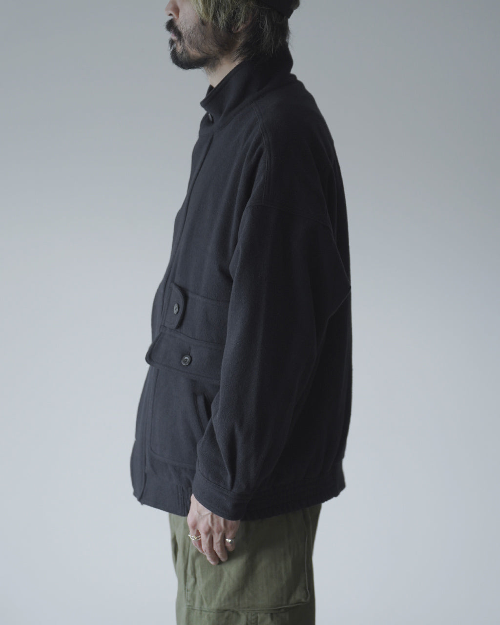 黒系のVESTE ABOSが横から見える着用イメージ。スタンドカラーと前立て、ポケットの配置が特徴的で、リラックスしたシルエットが分かる写真。