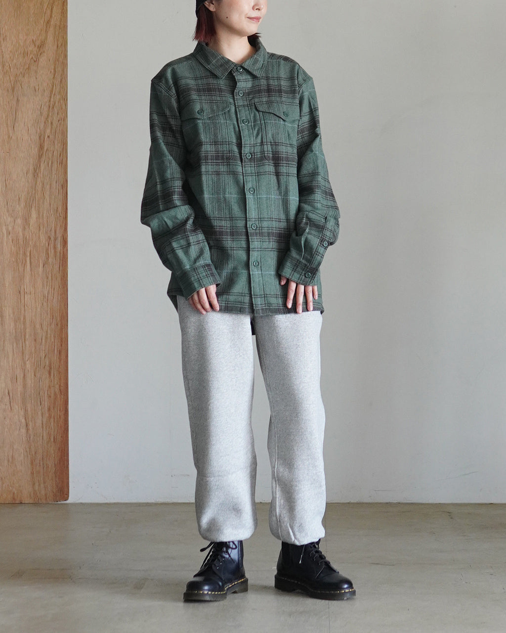 緑のチェック柄シャツを着たモデルの前後と横姿が分かる着用写真。ゆったりとしたシルエットで、胸ポケット付きのボタンシャツ、下はグレーのリブパンツと黒のブーツを合わせています。