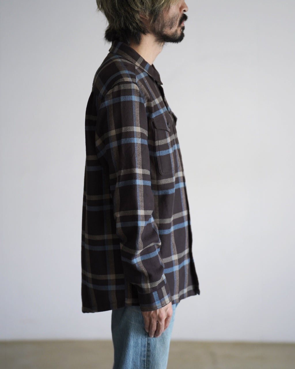 ブラウン系とブルーのチェック柄シャツ、サイドから見た着用イメージ。胸ポケット付きでゆったりとしたシルエットが分かる横からの視点