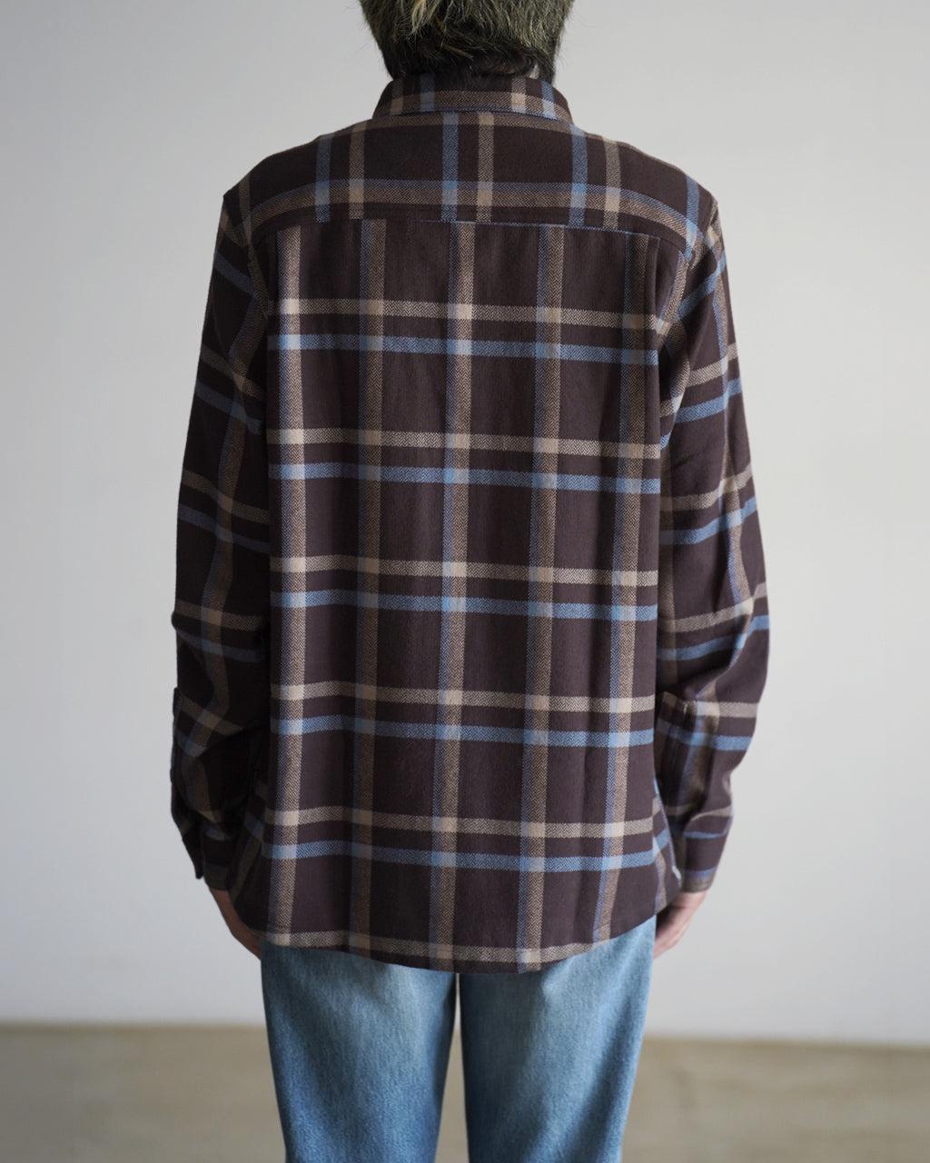 茶系のチェック柄シャツ後ろ姿。襟と長袖、腰付近までの丈感で落ち着いた雰囲気。淡いブルーの格子が特徴的なパタゴニアのシャツ