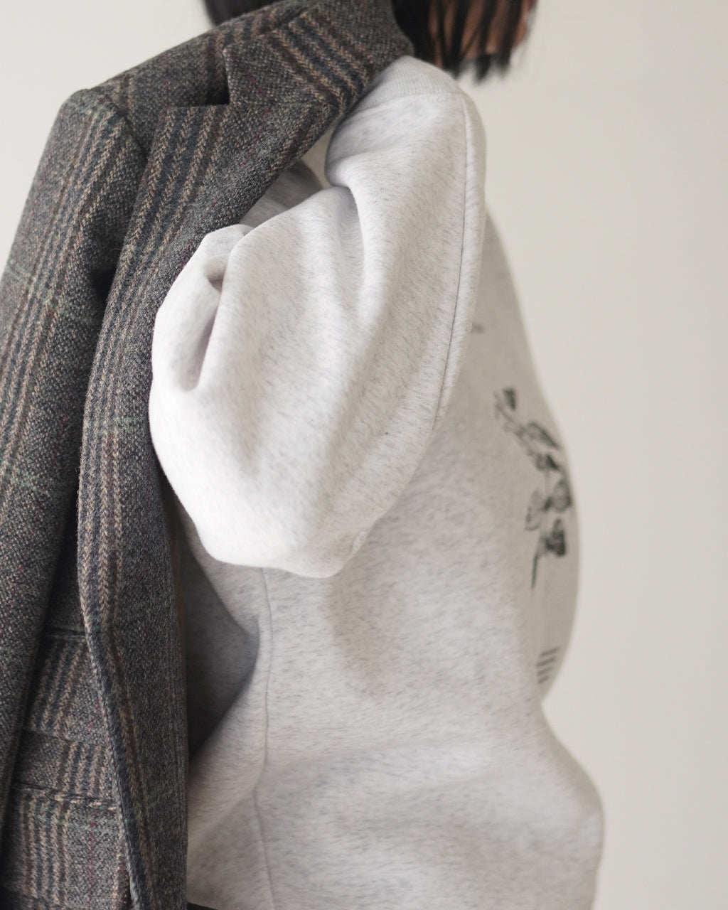 POET MEETS DUBWISEのBREATH OF PLANTS SWEATのグレー系スウェット。袖がややボリュームのあるクルーネック仕様で、背面に植物のデザインをプリントしている様子が見える横からのショットです。