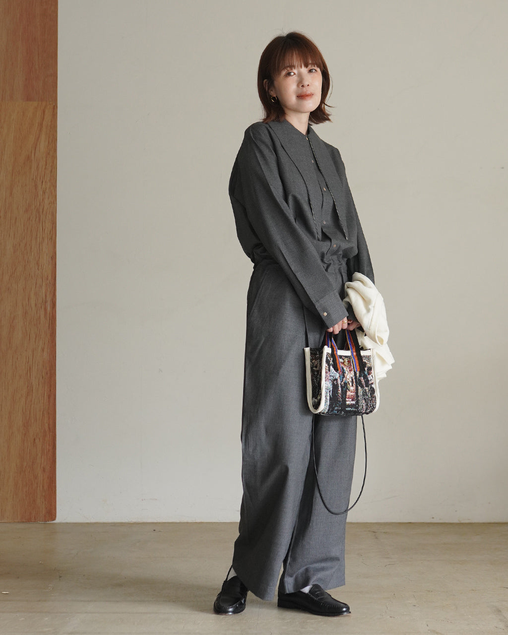 グレーのFine Worsted Jumpsuitの全身写真。シャツ風のトップスとワイドパンツを組み合わせたシルエットが分かる、襟付きのデザインを着用したモデルの姿。