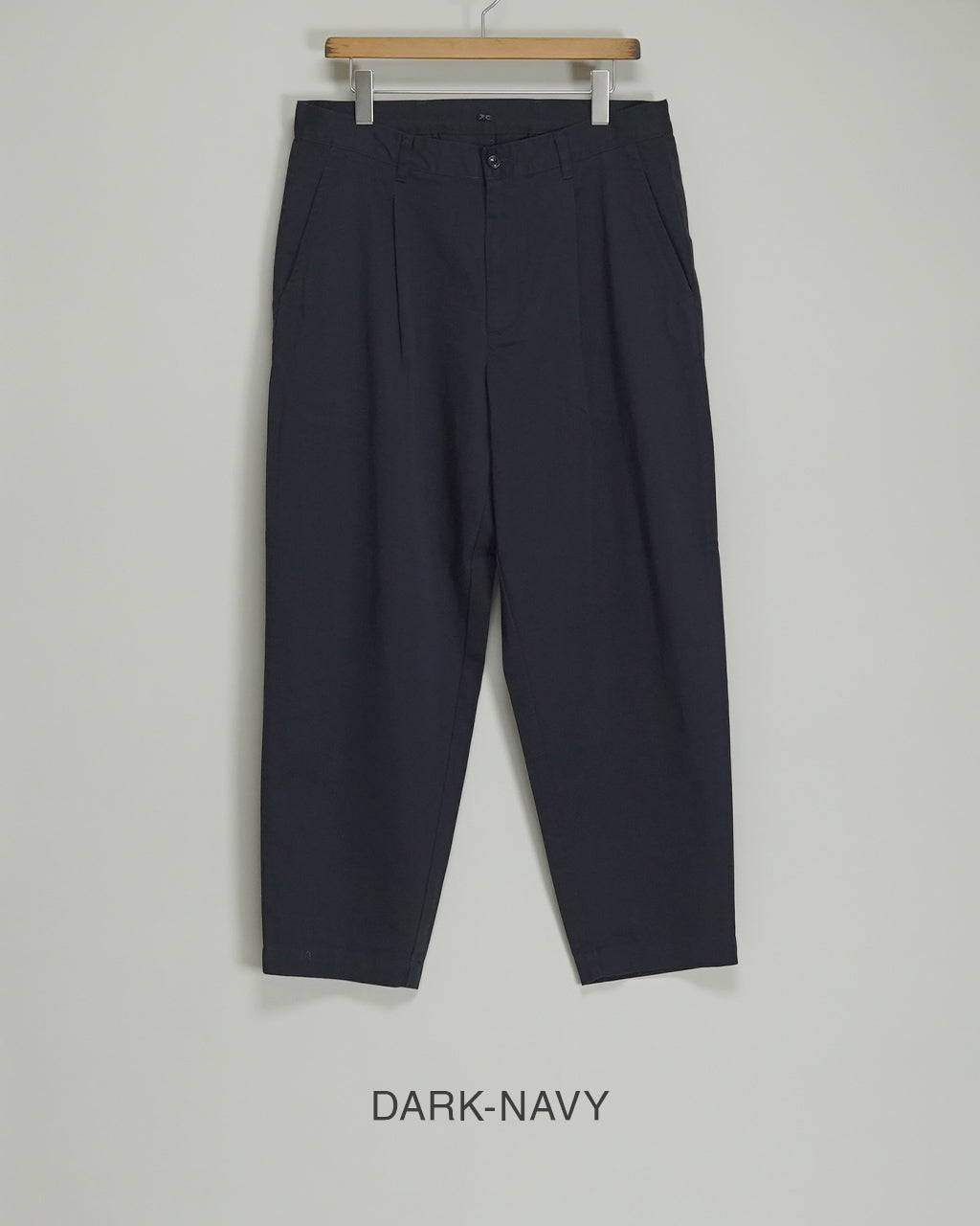 DARK-NAVYのチノパンツ。ウエスト周りに適度なゆとりを持ち、裾に向けてやや細くなるシルエットが特徴のパンツ。前開きとベルトループ、側面ポケットが見える。