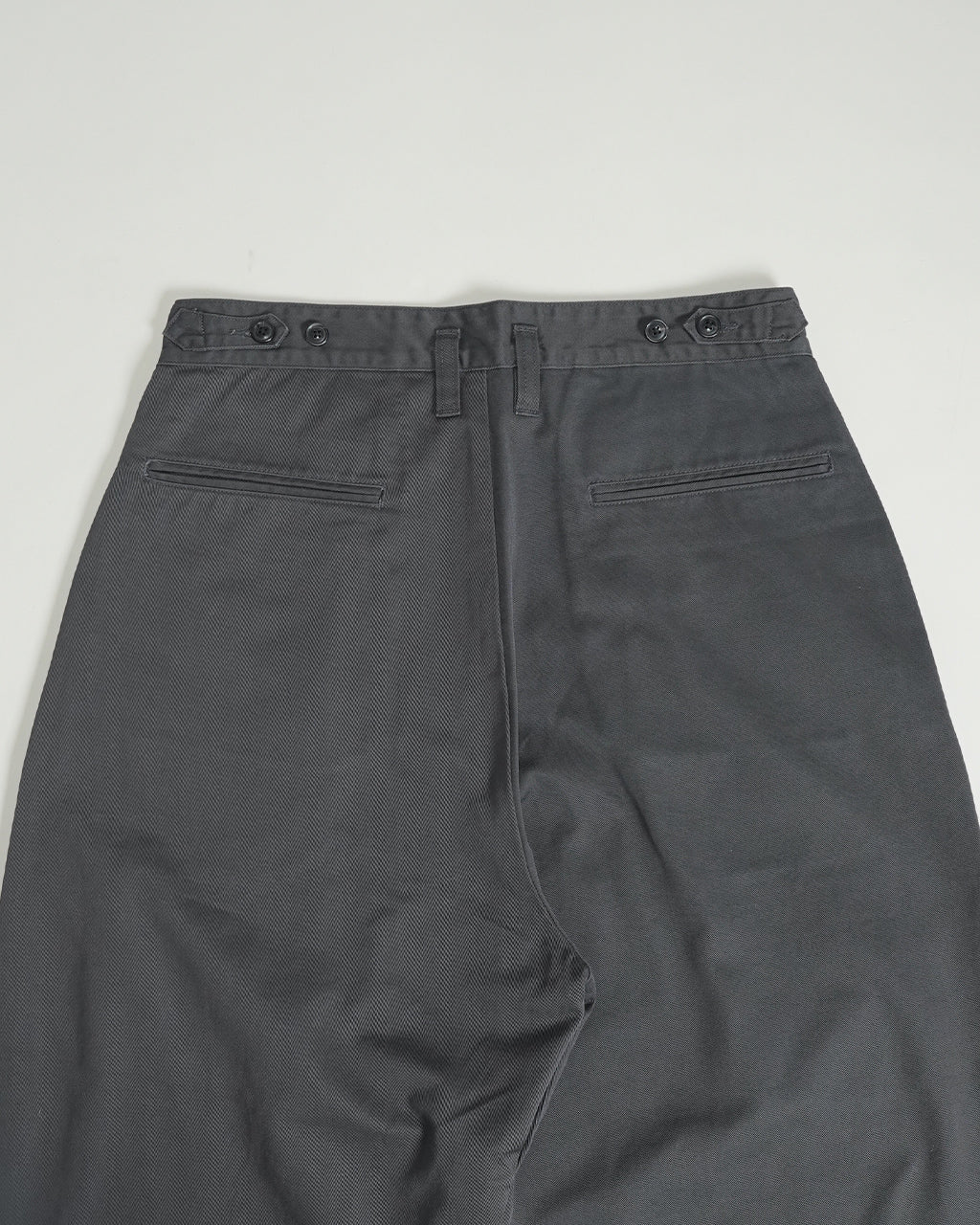 腰まわりにゆとりをもたせた PORTER CLASSIC のGENE KELLY CHINOS、後ろポケットは細長いテープ縫いの仕様でグレー系のチノクロス生地をアップに写したパンツの背面ショット