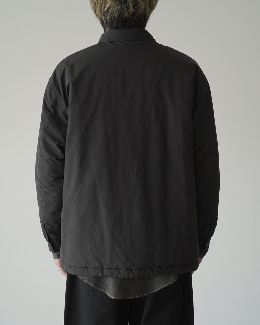 背面から映したポータークラシックの WEATHER COACH JACKET。ブラックのコーチジャケットで、ゆったりとしたシルエットと裾にやや長めのバックカーブが特徴的。