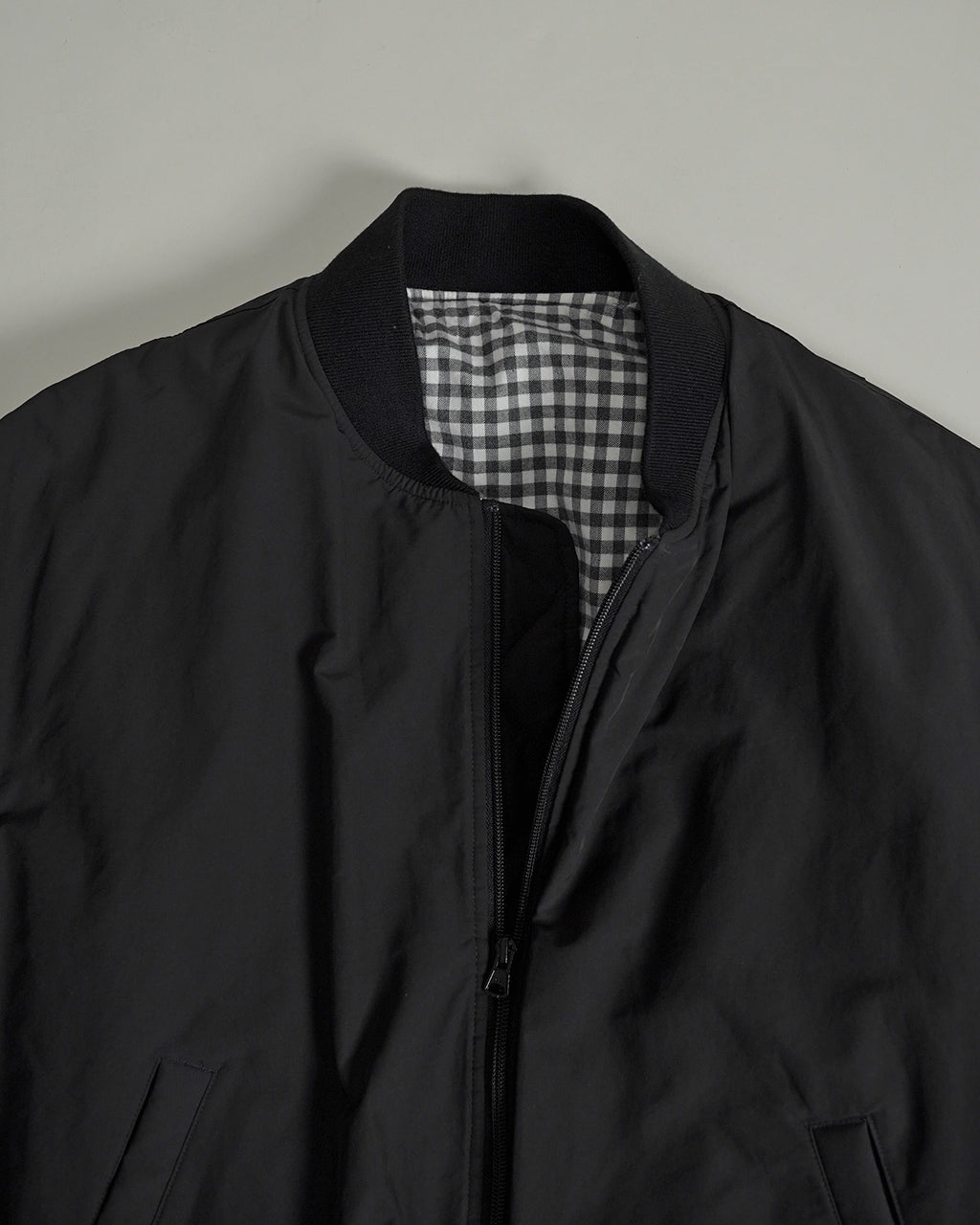 前開きジップと襟付きのボディラインが映える、黒の WEATHER FLIGHT JACKET。内側はチェック柄の裏地で、立ち上がり防寒にも配慮したシンプルなディテールのジャケットです。