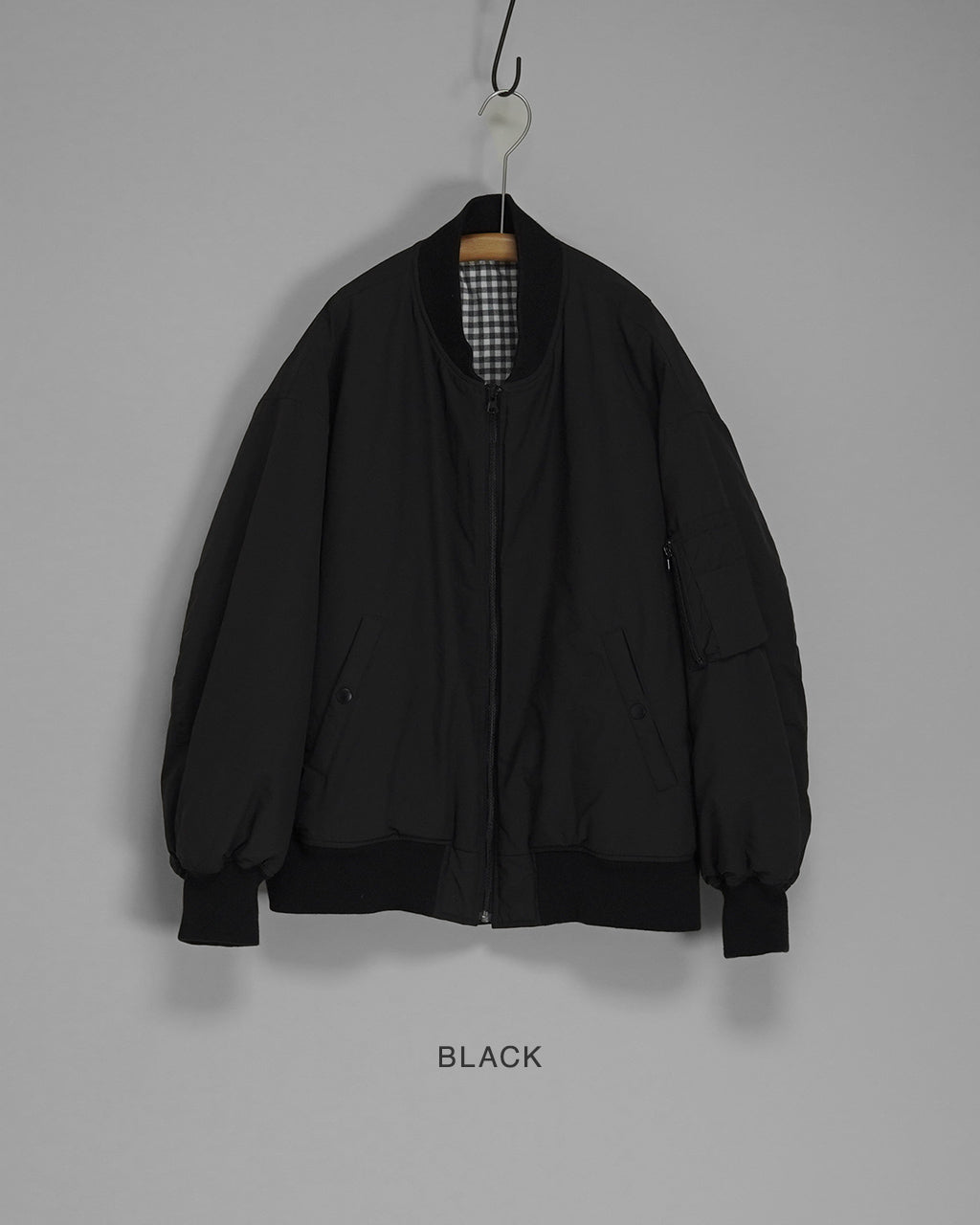 前面から掛けられたブラックの WEATHER FLIGHT JACKET。ジッパー開閉式で、裾と袖口はリブ仕様。胸ポケットと両サイドポケットのディテールが見える