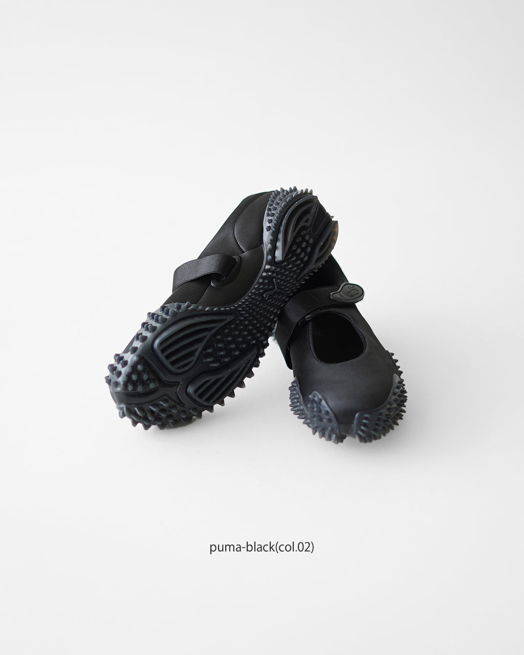 ブラックカラーのPUMA Mostro Fey Satinを白背景で並べたカラービジュアル。ソールの突起と丸いフォルムが分かる
