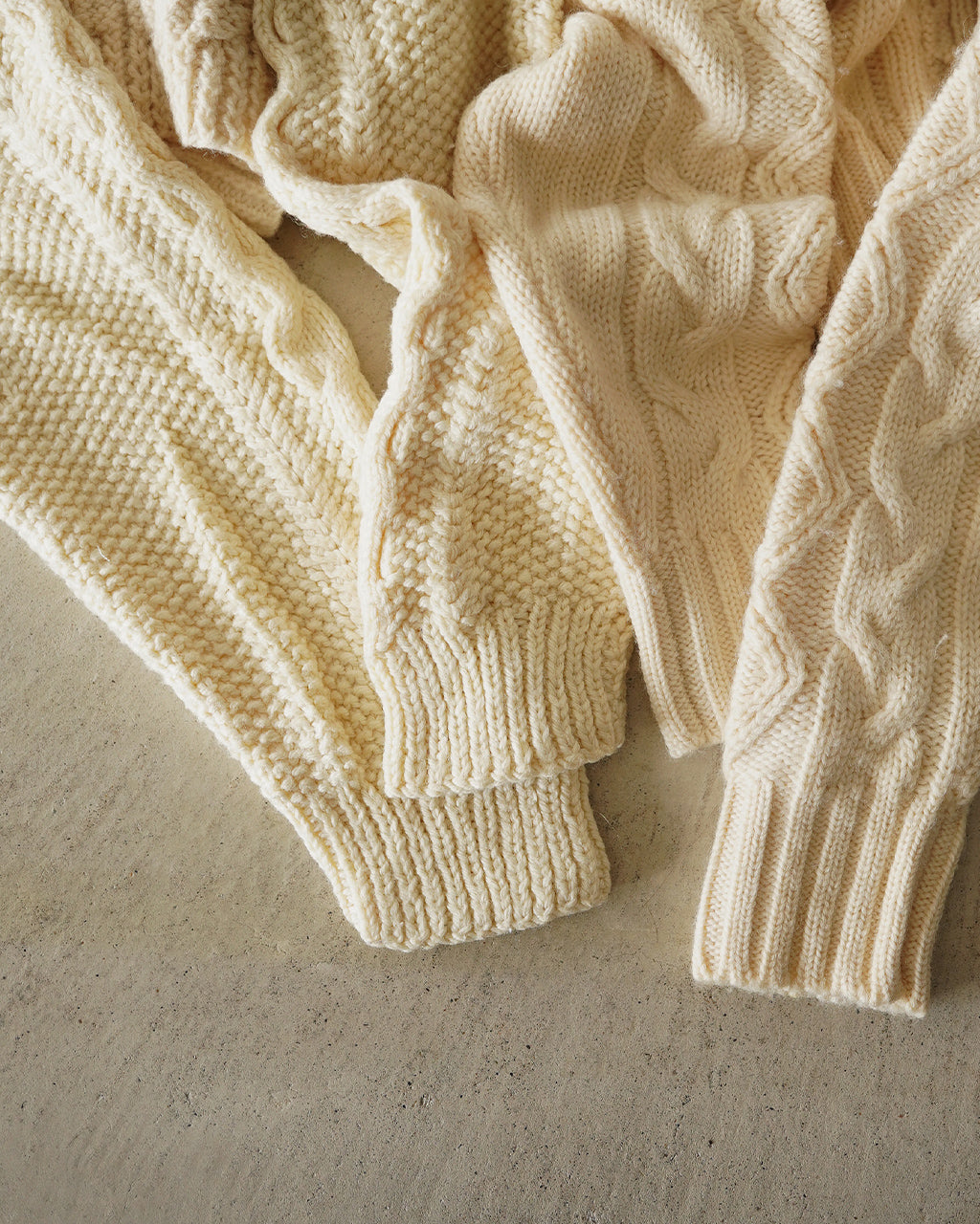 オフホワイト系の編み地を寄せたリメイクニットの袖口と袖部分をクローズアップ。凹凸のある編み柄が特徴で、柔らかな生成り色の素材感が伝わるディテール写真。