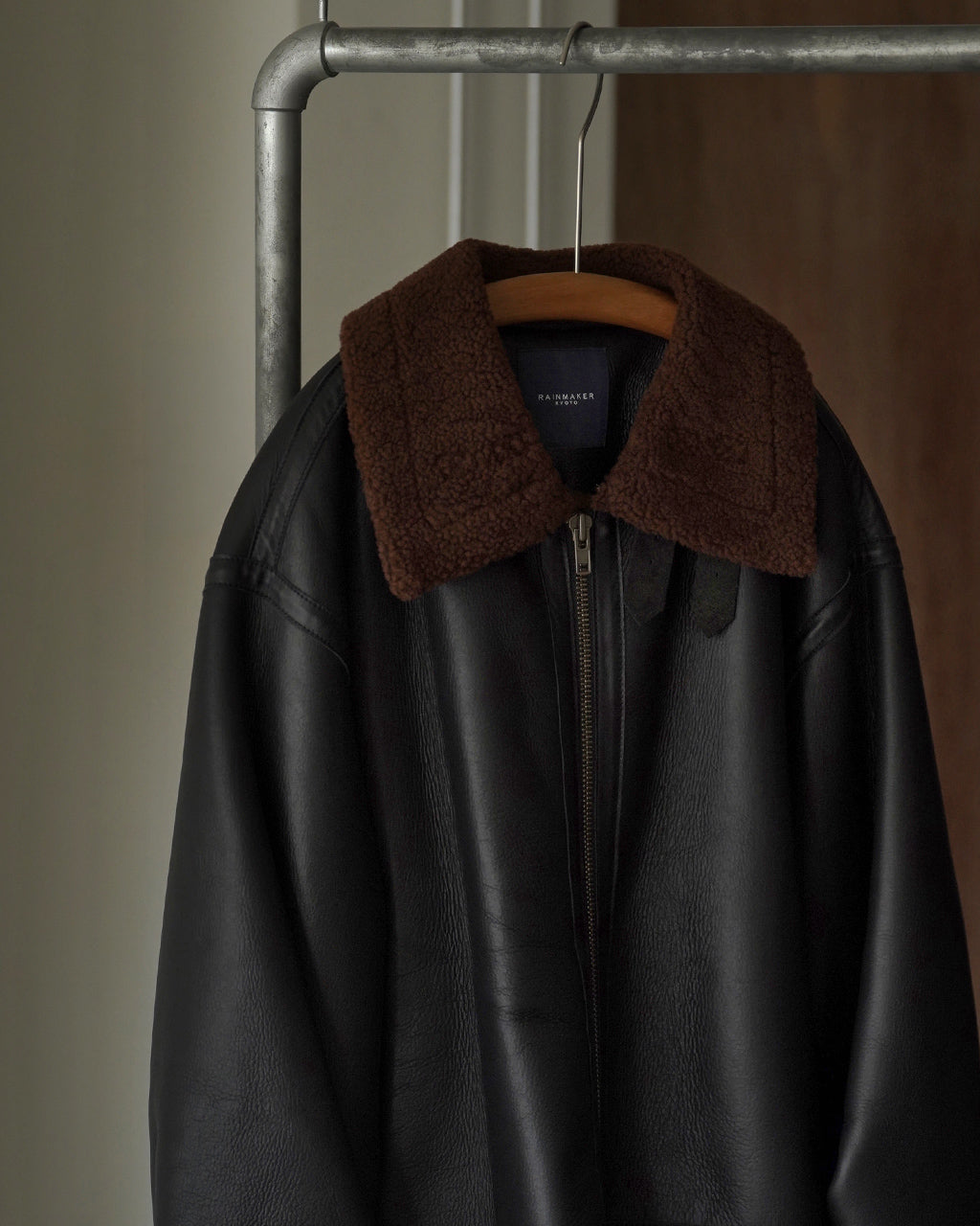 ブラックのボアライニング付きレザージャケット。前中心のファスナーと大きな襟を備え、 hanger にかけられた状態で全体像が見える。