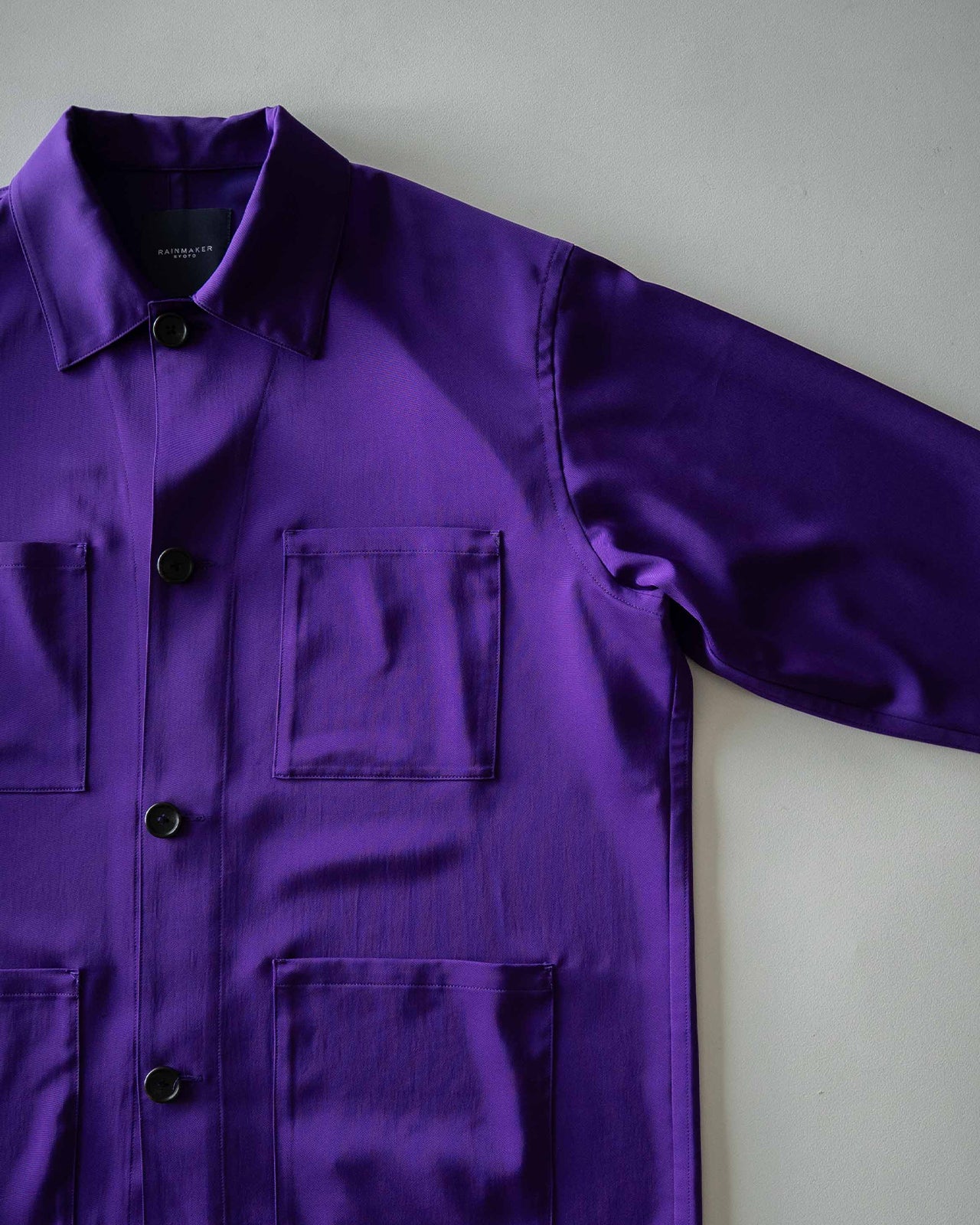 紫色のSUPPLE WORK SHIRT RM262-016の前身頃アップ。胸ポケットとボタンが見え、光沢感のあるトリアセテート混紡生地が確認できる。袖は半袖で肩幅が広めのシルエット。
