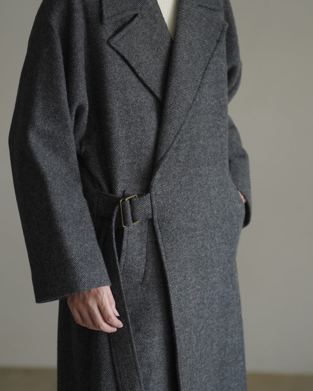 ダークグレーのWRAP COAT RM262-034のサイドショット。着物のような大らかな布量とウエストベルトのディテールが映える、表情豊かな質感の中厚手のコート