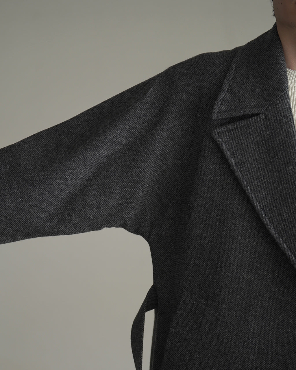 グレーのWRAP COAT RM262-034の袖を広げた正面寄りのディテール。厚みのある生地の凹凸と襟周りの縫製が際立つ写真。