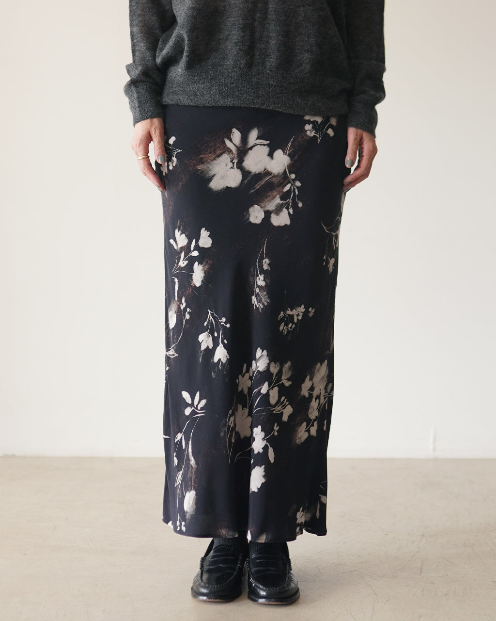 黒地に白と茶系の花柄を散らしたロングスカート。ストレートなナローラインで、歩くたびに柔らかく揺れるディテールが印象的。