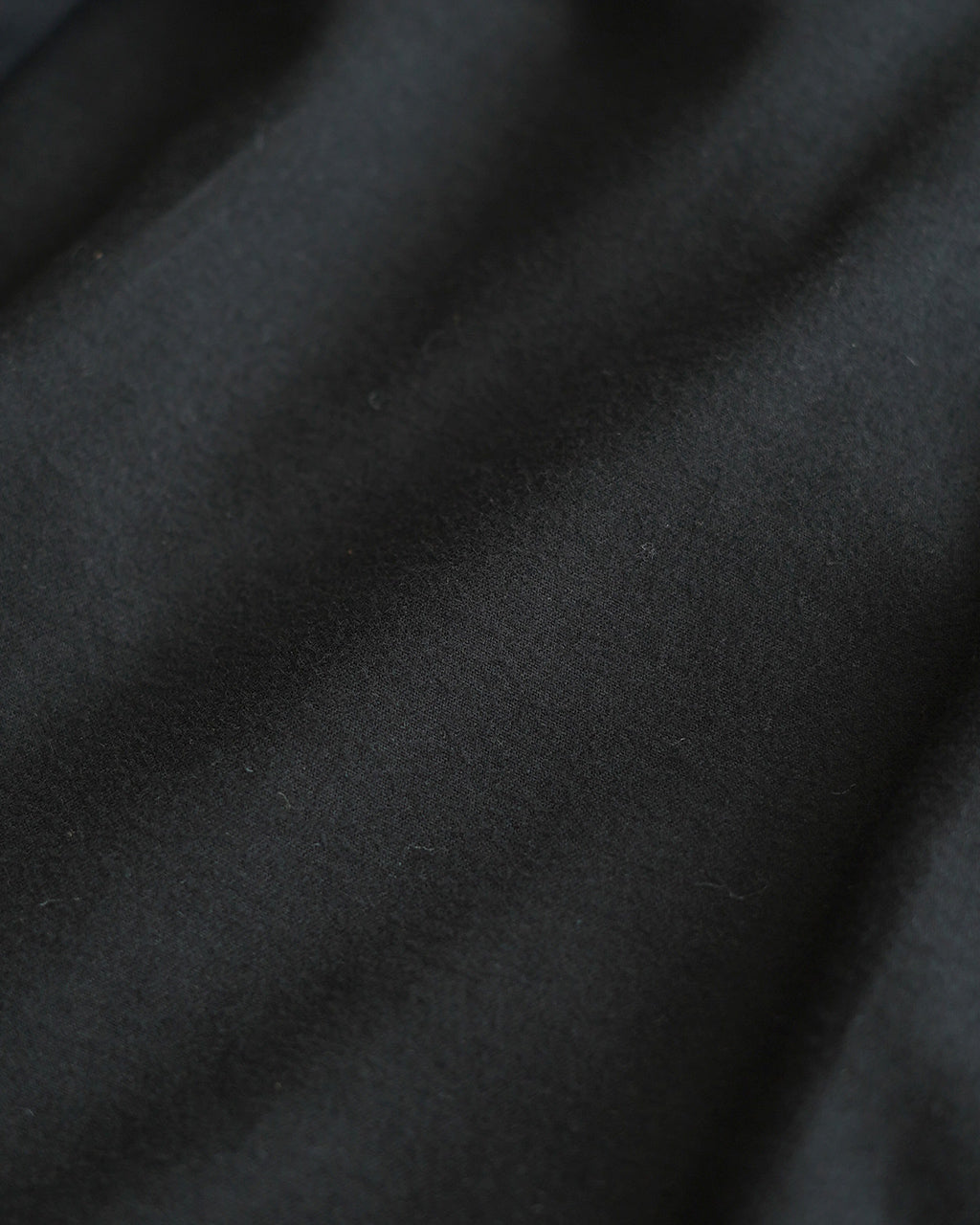 SACRA Cavarly Twill Jacketの近接撮影。 コットンツイル生地のしなやかな質感と深いブラックの色味が伝わるディテール画像。