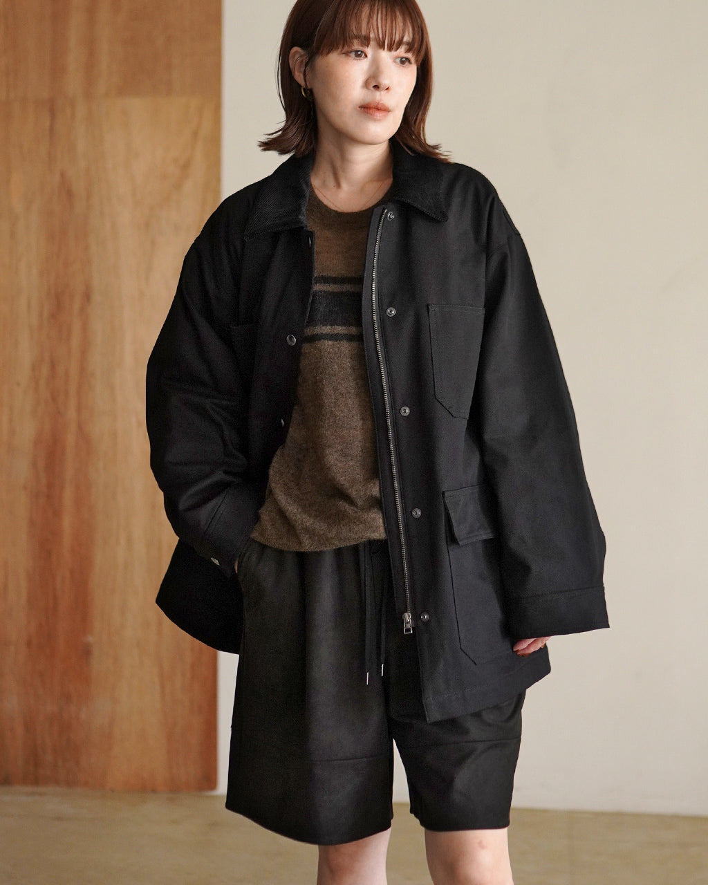 ブラックのCAVALRY TWILL JACKETを着た女性モデルの前後開きデザイン。ゆったりシルエットで裾に向かって緩やかに広がり、胸元の大きなポケットとジップが特徴的。