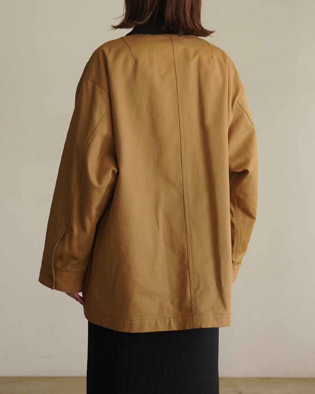ベージュ系のCAVALRY TWILL JACKET後ろ姿。ゆったりしたオーバーシルエットで丈は腰あたり、背面の縫い目が強調されている着用イメージ。