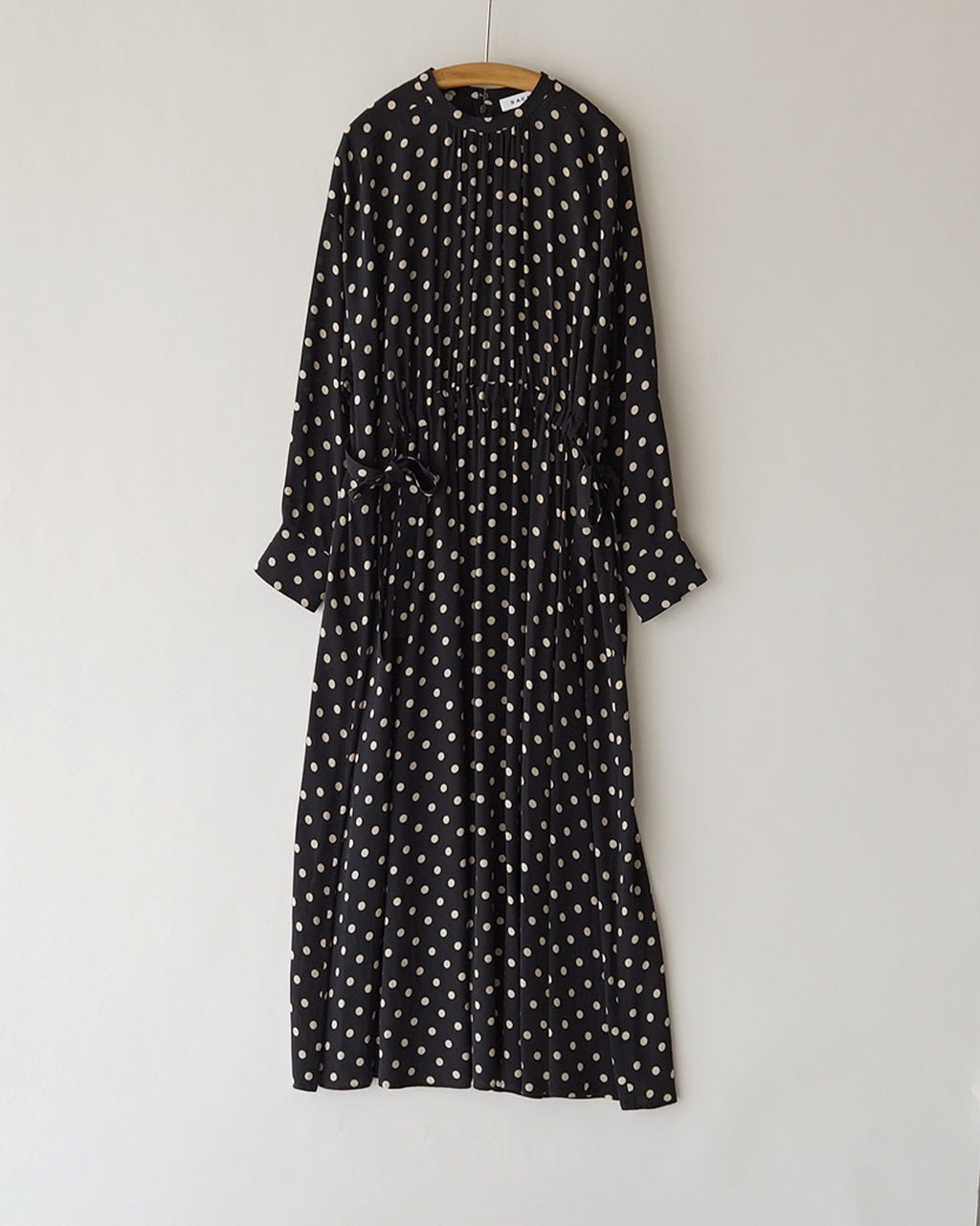 黒地に白いドットが散らばる Polka Dot's OP の正面全身ショット。ウエストを絞ったデザインと長さのあるシルエットが特徴的です。