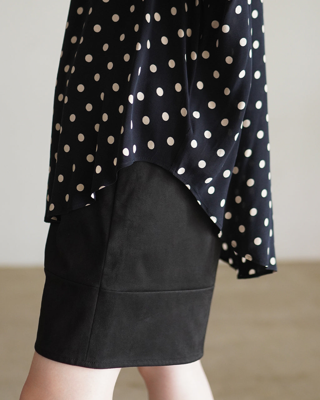 黒地に白ドットが散らばるPolka Dot's Shirtのサイドからのぞく裾回り。波打つドレープが特徴的で、丈は下に向かって少し長めに見えるデザイン。
