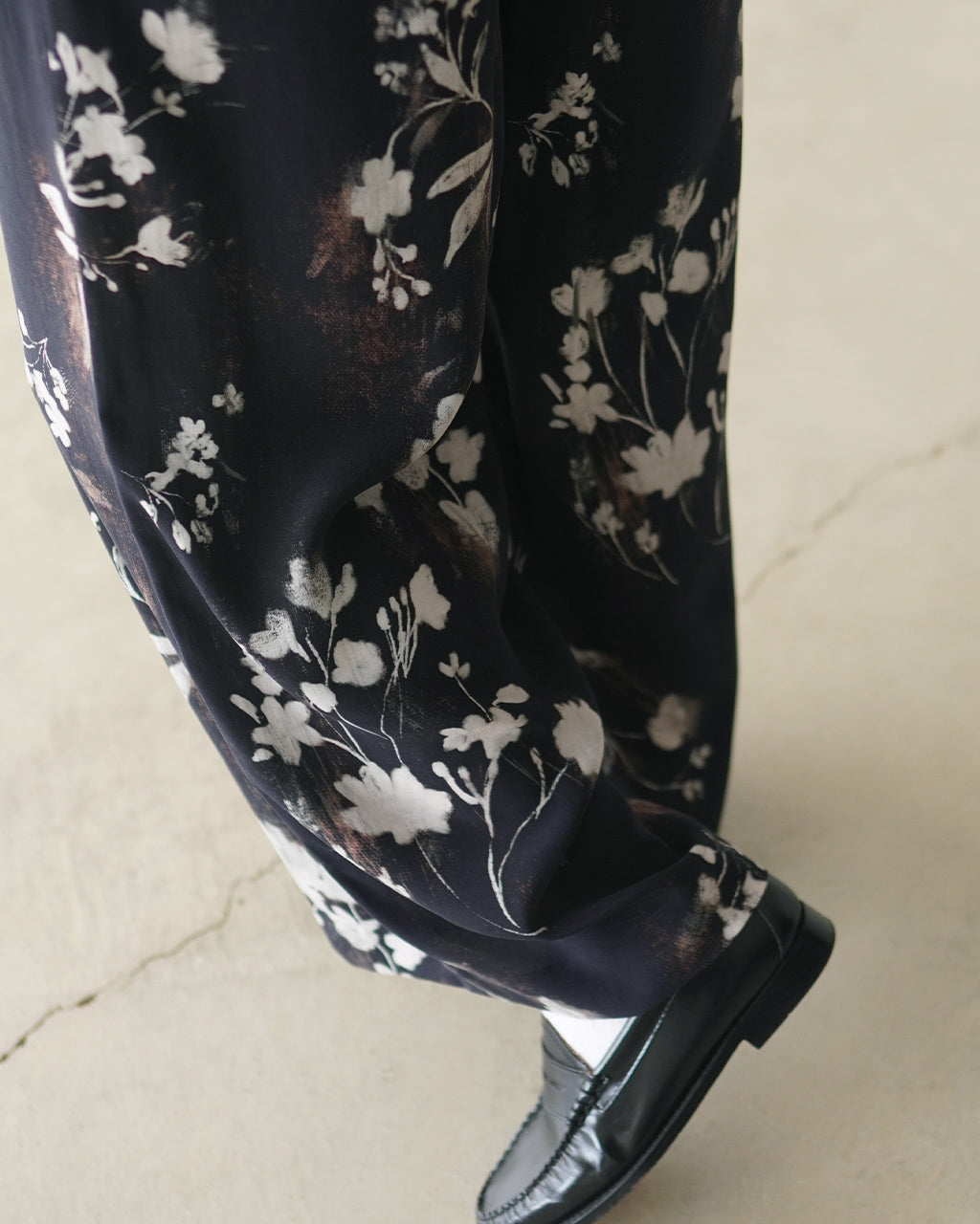 黒地に白花柄のパンツ生地アップ。花柄が抽象的に描かれ、透けず滑らかなドレープ感が伝わる布地の質感ショット