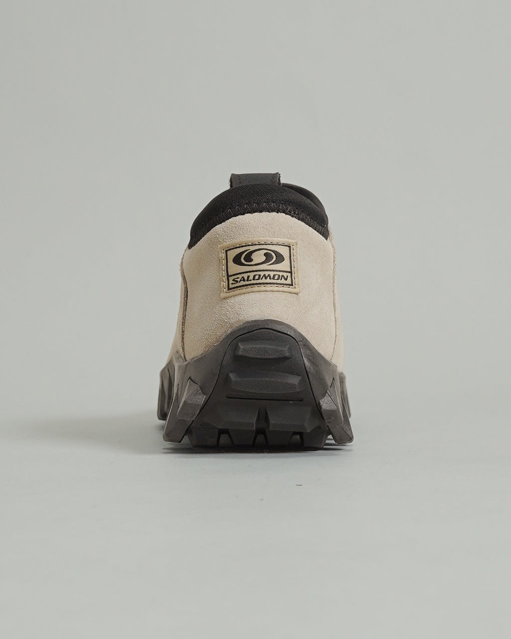 後方から撮影されたベージュ系のサロモンSNOWCLOG OG。黒いアウトソールとブランドロゴのワッペンが背部に配置され、足首周りはブラックのパッドで包まれている