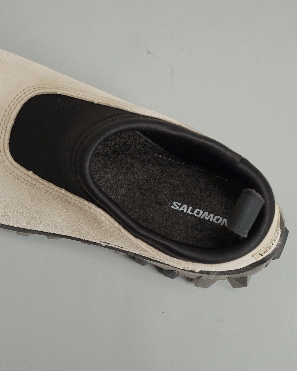 サロモン SNOWCLOG OG のベージュ系アッパー部分と黒いインナーが見えるスリッポン型のデザイン。側面とつま先のラインが際立ち、アウトソールの凹凸も確認できる写真。