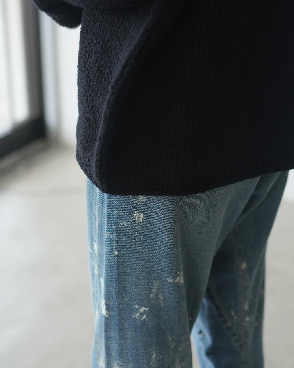 黒のふっくらとしたニットとインディゴデニムの組み合わせ。毛足の表情が際立つ生地感を近距離で捉えたディテール写真。