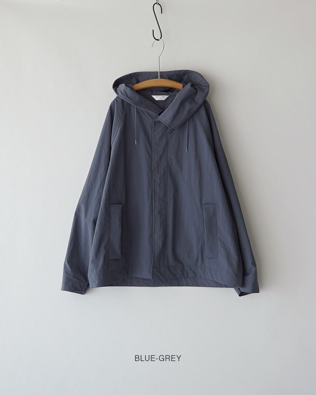 フード付きの薄手ブルゾン。胸元の重ねデザインと前身頃のポケットが特徴的で、BLUE-GREYの色味が落ち着いた印象です。