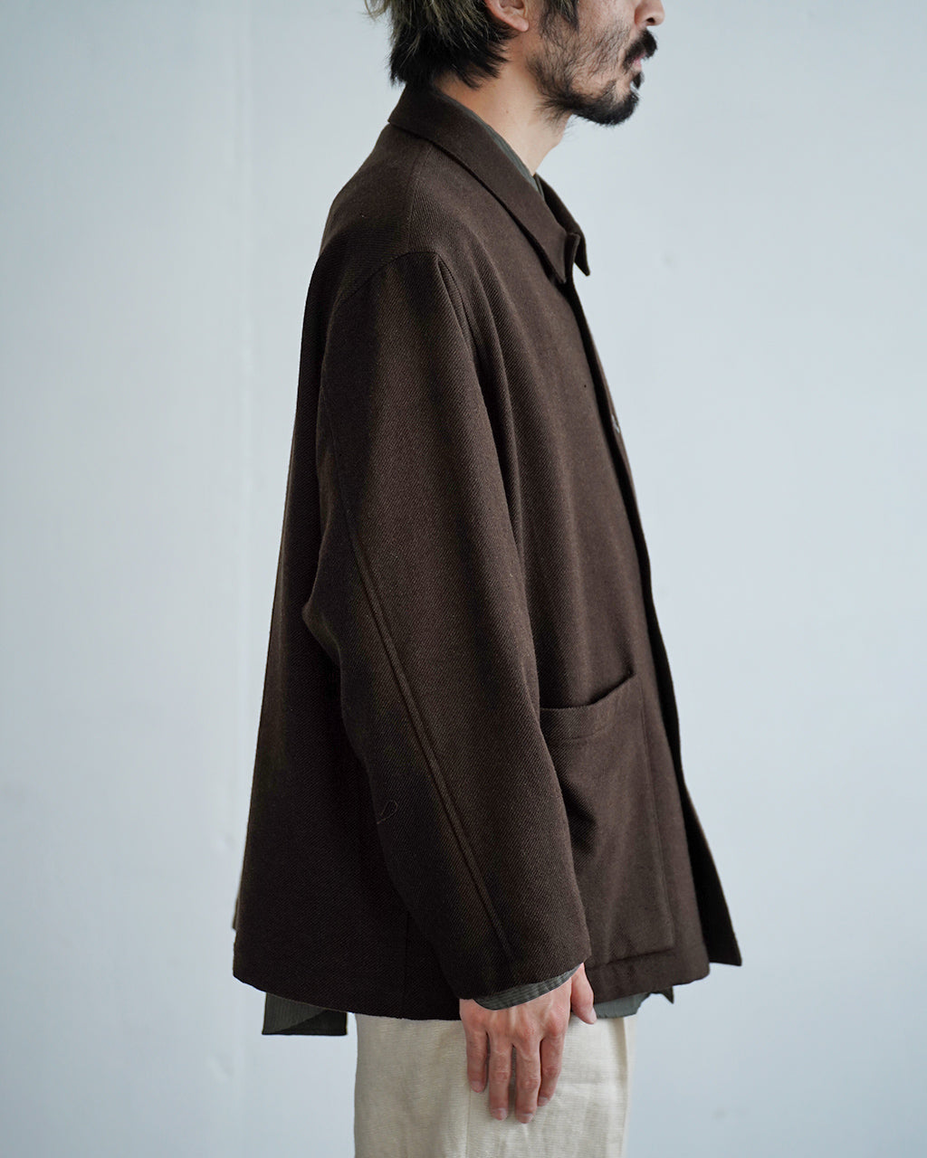 深い茶系の Wool mixed 4B jacket の横から見たシルエット。ゆとりのある袖と大きめの襟が特徴で、裾は前後がやや長めの丈感。
