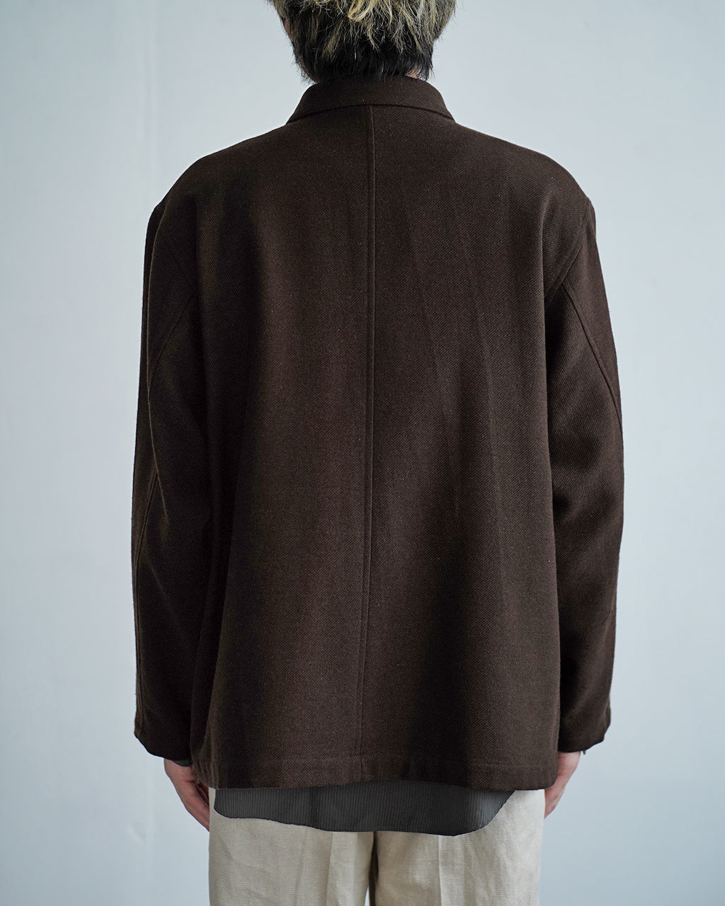 焦点はダークブラウンの Wool mixed 4B ジャケットの背面。ゆったりとしたシルエットと大きめの襟、4つボタンの前立てを持つディテールが特徴的に見える後姿の写真。
