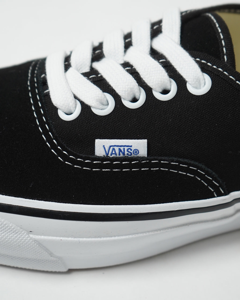 ブラックキャンバスとスエード素材のVANS LX Authentic Reissue 44のアップショット。白い靴紐とステッチ、ロゴ付きタグが際立つディテール写真