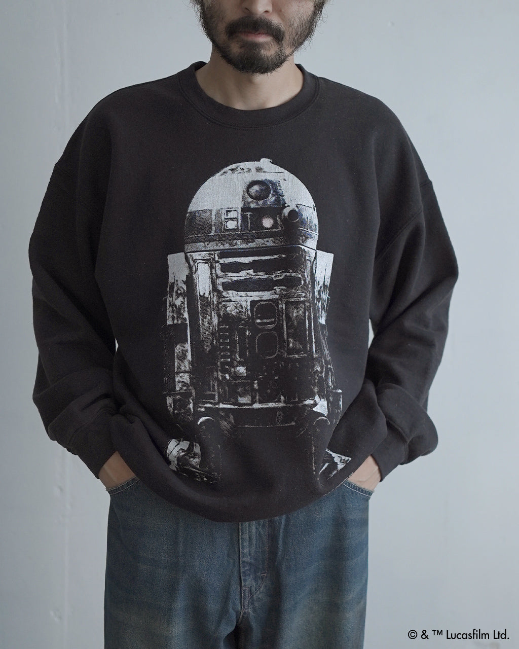 ブラックの長袖スウェットにR2-D2のモノクロプリントが大きく入ったデザイン。袖や裾はリブ仕様で、ゆったりとしたシルエットの着用イメージ。